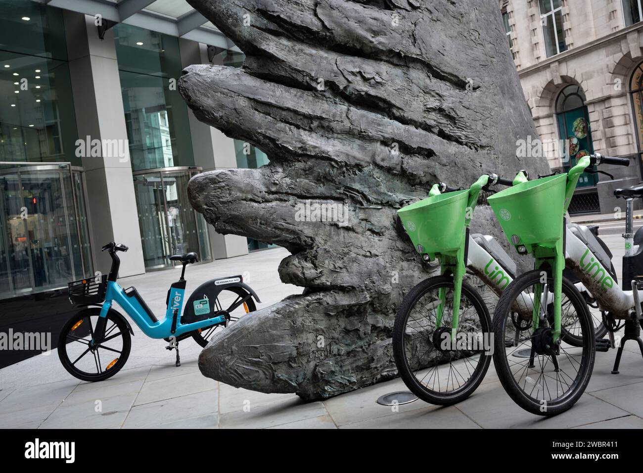 Limettenverleih-eBikes werden zusammen unter der Skulptur „City Wing“ in der Threadneedle Street geparkt, der Straße in der City of London, dem Finanzviertel der Hauptstadt, am 11. Januar 2024 in London, England. City Wing stammt von dem Künstler Christopher Le Brun. „City Wing“ ist eine zehn Meter hohe Bronzeskulptur des Präsidenten der Royal Academy of Arts, Christopher Le Brun, die 2009 von Hammerson in Auftrag gegeben wurde und von Morris Singer Art Gründern gegossen wurde, der angeblich ältesten Kunstgießerei der Welt. Stockfoto