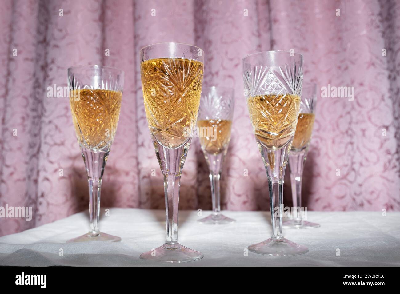 Fünf Kristallgläser mit Champagner auf einem Vorhang, Konzept im Stil der 90er Jahre Stockfoto
