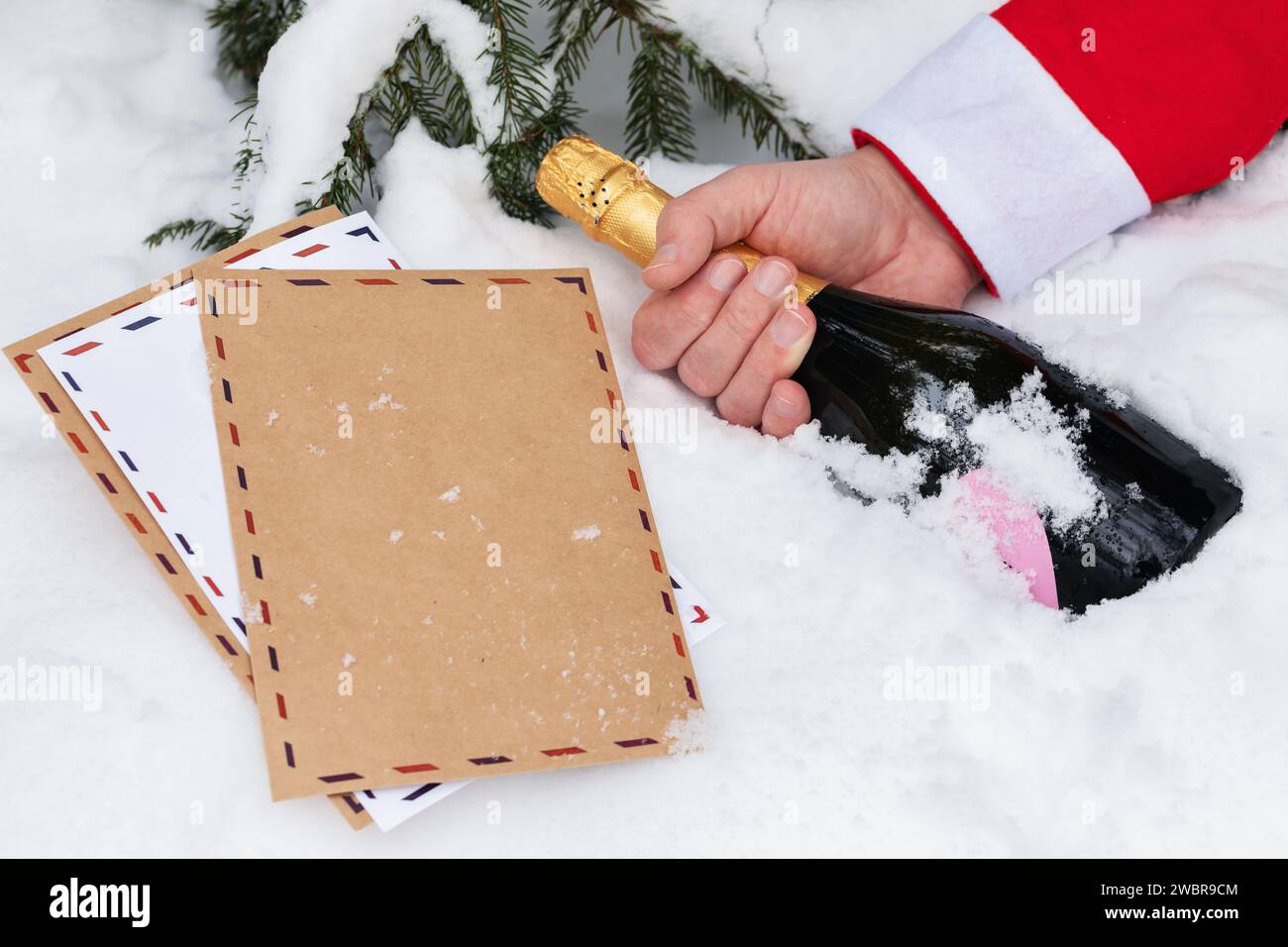 Weihnachtsbriefe und Weihnachtsmann Hand mit einer Flasche Champagner auf dem Schnee, Konzept zum Thema "schlechter Weihnachtsmann, der Kinderbriefe verliert" Stockfoto