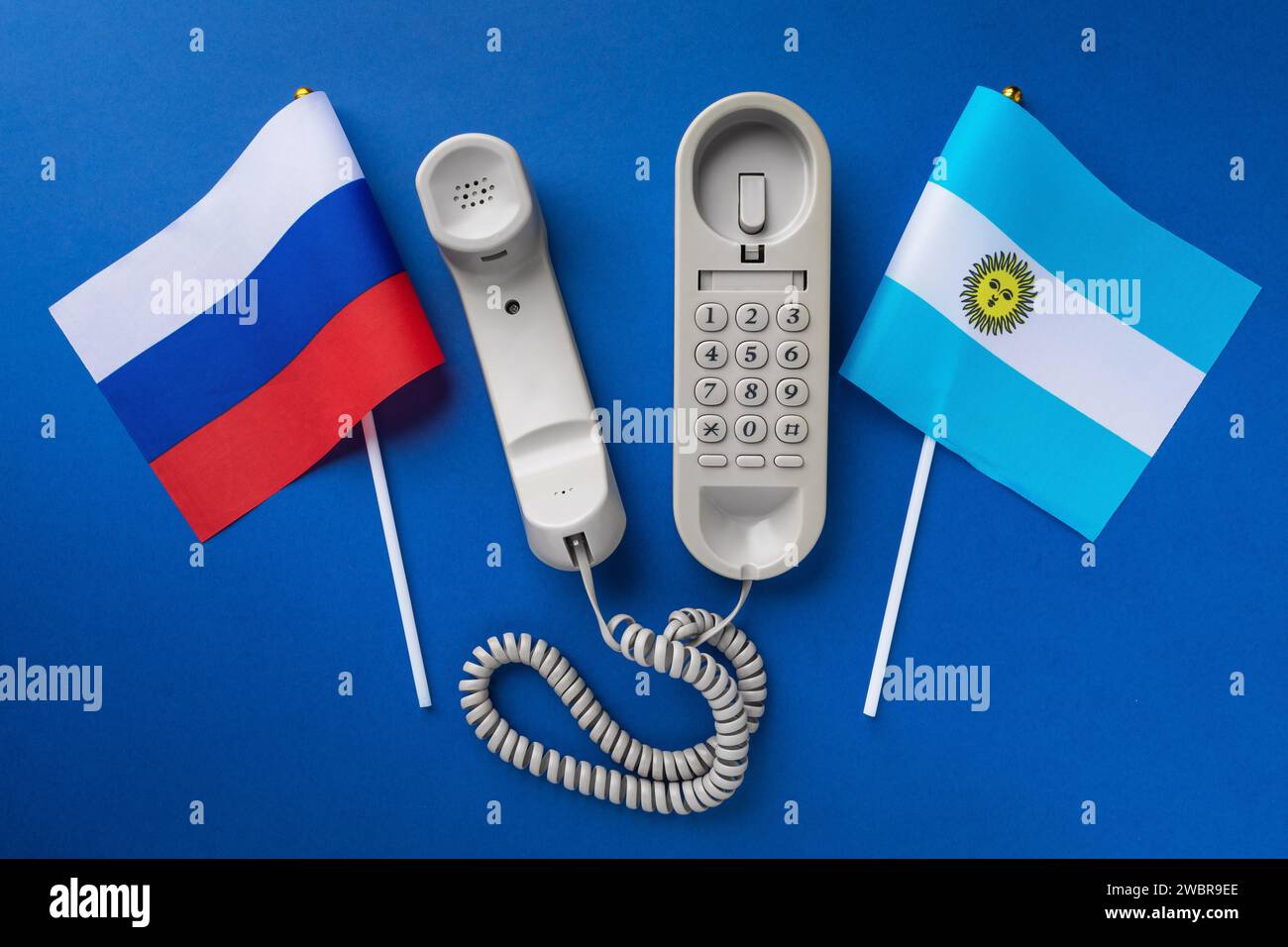 Altes Telefon und zwei Flaggen auf blauem Hintergrund, Konzept zum Thema Telefongespräche zwischen Argentinien und Russland Stockfoto