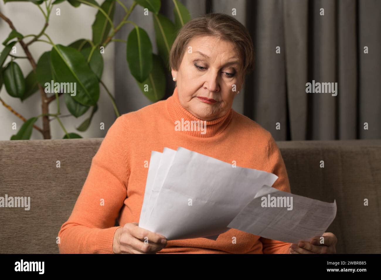 Porträt einer alten Frau, die im Sitzen Rechnungen ansieht Stockfoto