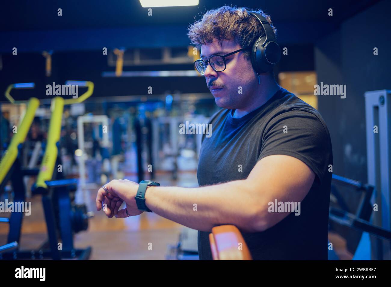 Der Mann beobachtet seine Uhr, während er trainiert und Musik hört Stockfoto