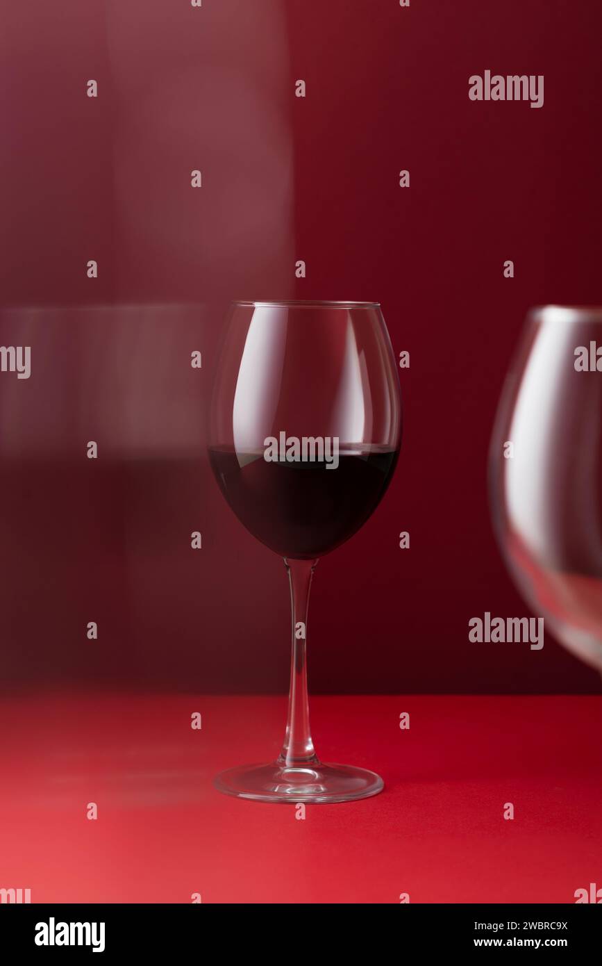 Glas Rotwein auf rotem Hintergrund Kunstfotografie Stockfoto