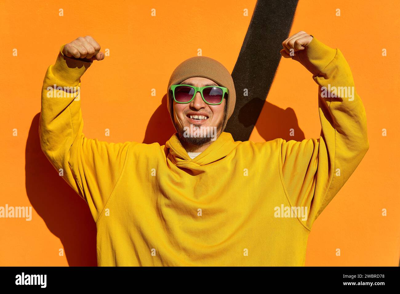Ein stylischer Kerl in einem gelben Kapuzenpullover posiert für die Kamera gegen die Stockfoto