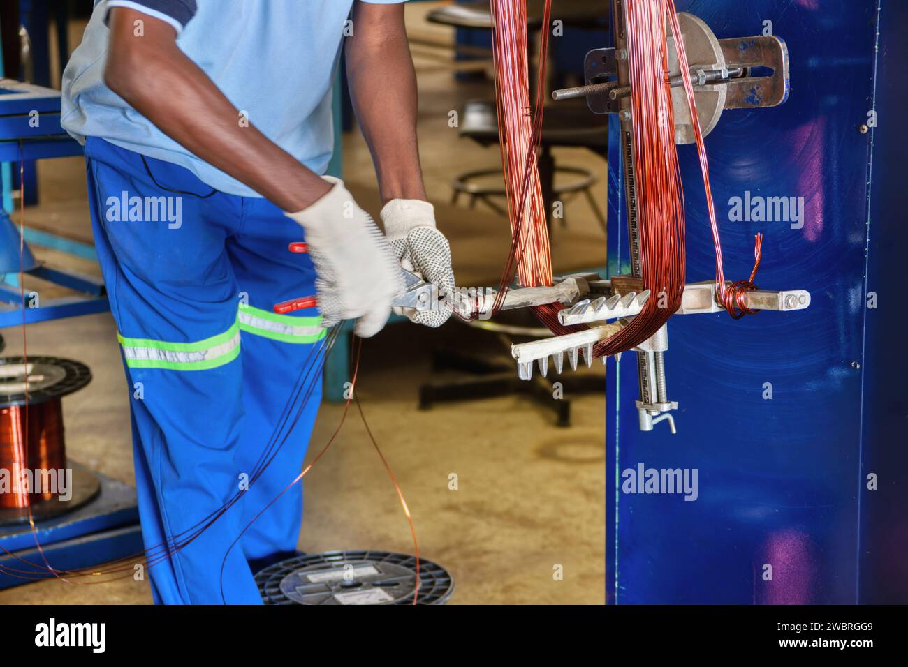 Elektromotor umwickeln, afrikanischer Mann wickelt Kupferdraht auf Stockfoto