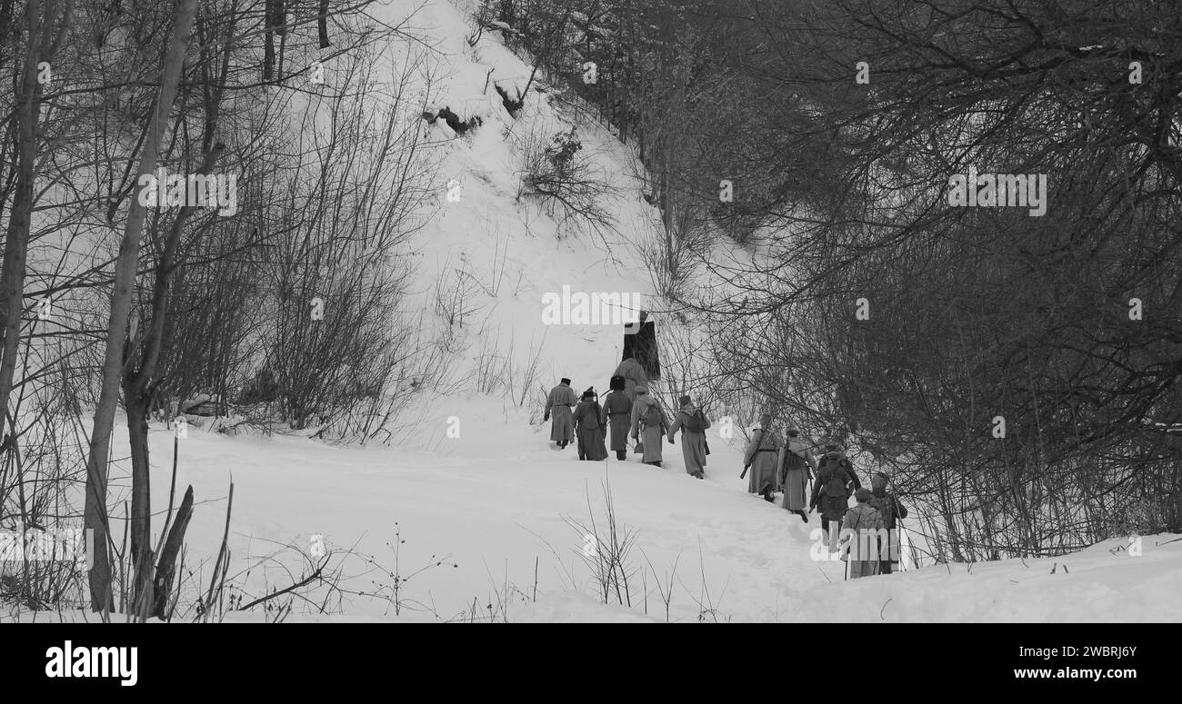 Als Soldaten der Weißen Garde verkleidete Männer der kaiserlichen russischen Armee im russischen Bürgerkrieg, die durch den schneebedeckten Winterwald marschieren. Historische Nachstellung von Stockfoto