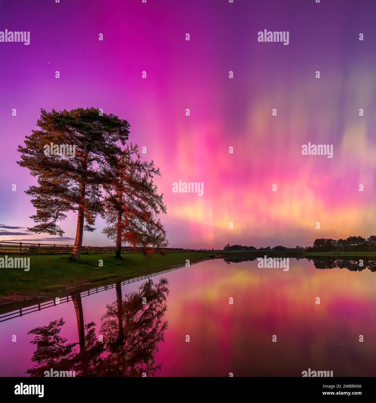 Ein farbenfroher Blick auf die Nordlichter Aurora Borealis spiegelt sich im Whittle Dene Reservoir in Northumberland unter klarem Winterhimmel wider Stockfoto