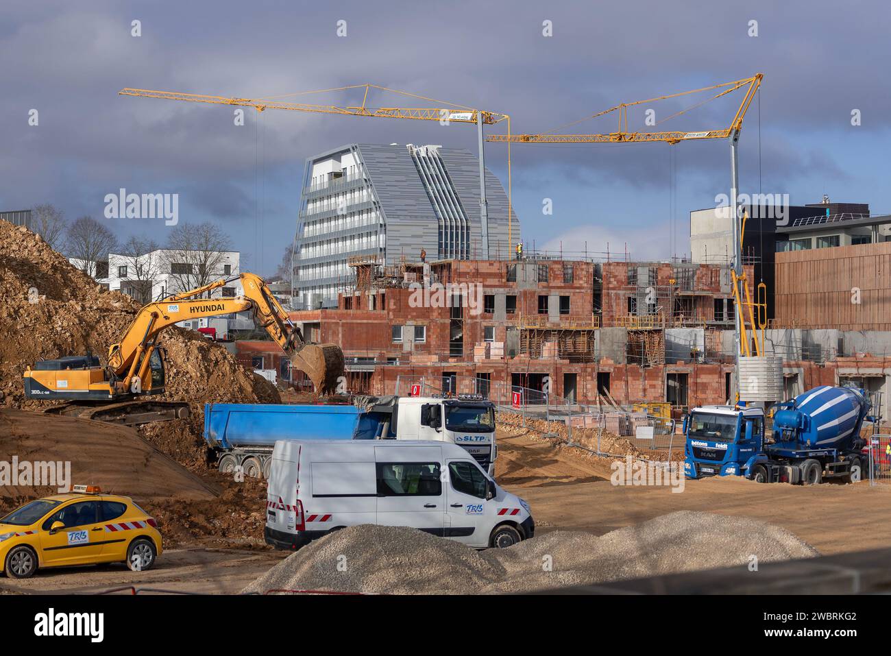 Selbstaufrichtende Krane Potain Hup 40-30 und IGO 50 auf einer Baustelle und einem Gebäude im Bau mit einem modernen Gebäude im Hintergrund. Stockfoto