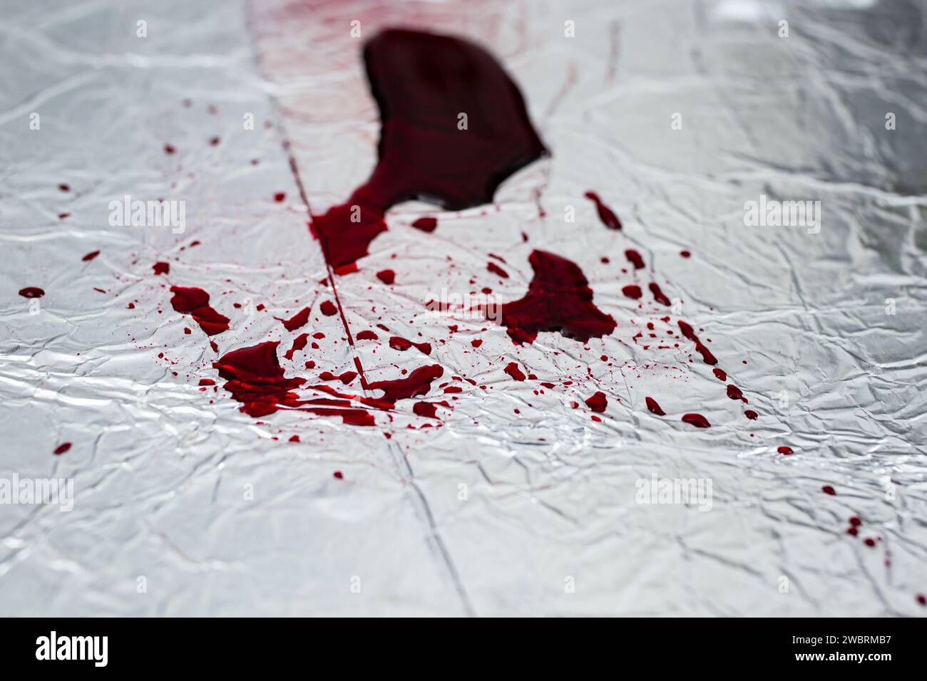 Rote Blutspritzer auf silberner Stahloberfläche, Weichzeichner, abstrakter Hintergrund Stockfoto