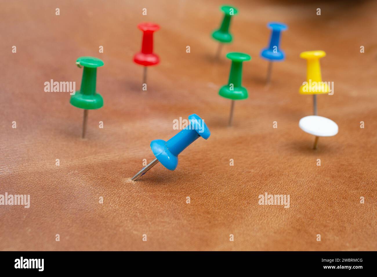 Farbenfrohe Stecknadeln in braunem Echtleder getaucht, weicher Fokus Stockfoto