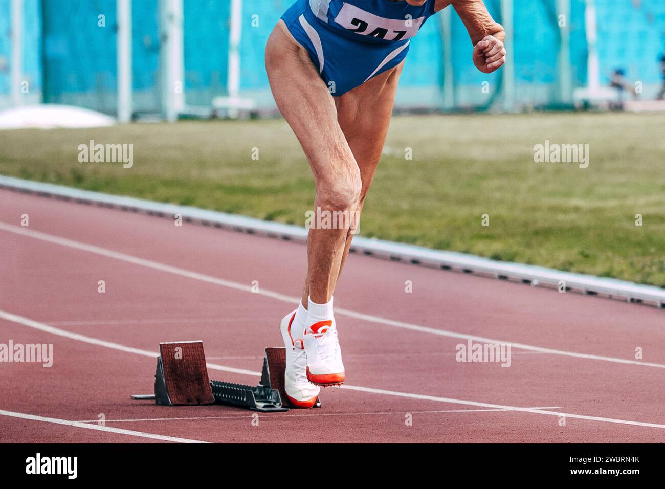 Senior-Läuferin, die aus den Startblöcken im Sprintrennen in der Meisterathletik läuft Stockfoto