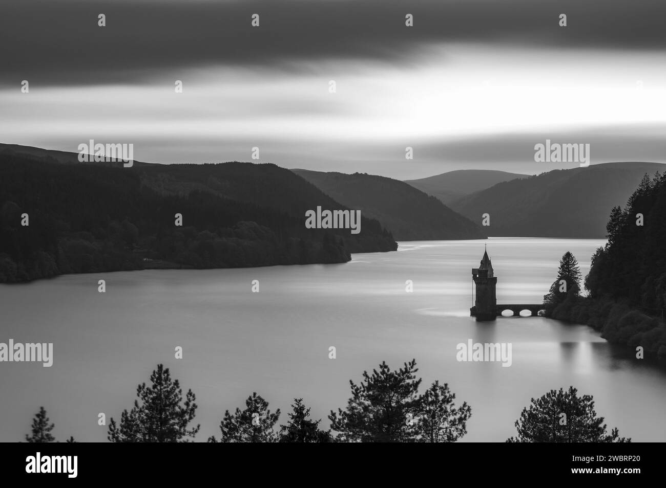 Langlebigkeit, schwarz-weiß, des Lake Vyrnwy in Mid Wales. Es gibt eine Pumpstation, die in den See ragt, der von üppigem Grün umgeben ist Stockfoto