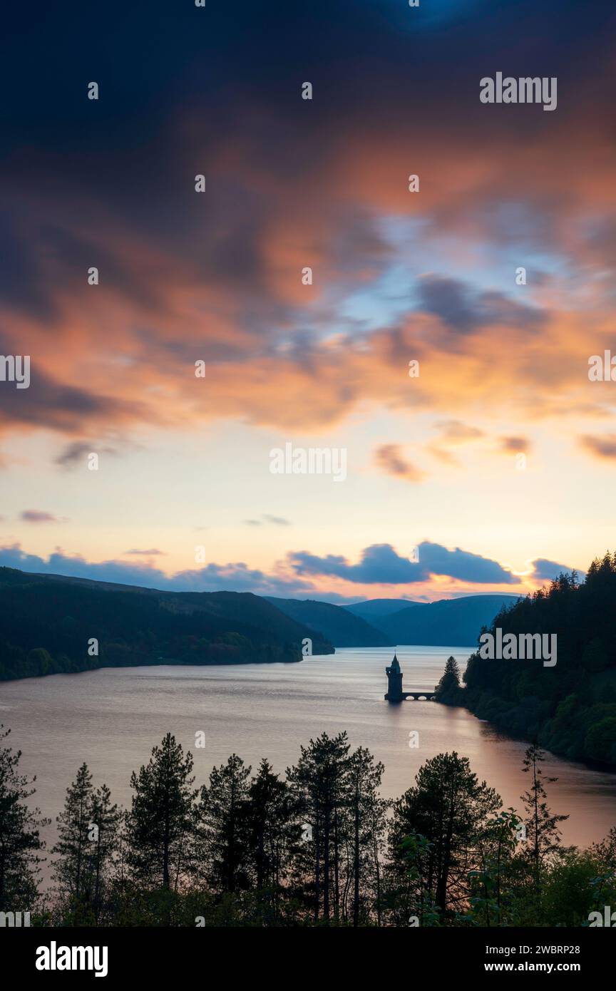 Lake Vyrnwy, in der Mitte von Wales, einer Gegend von außergewöhnlicher natürlicher Schönheit, bei Sonnenuntergang. Der orange Himmel spiegelt sich im ruhigen Wasser des Sees Stockfoto