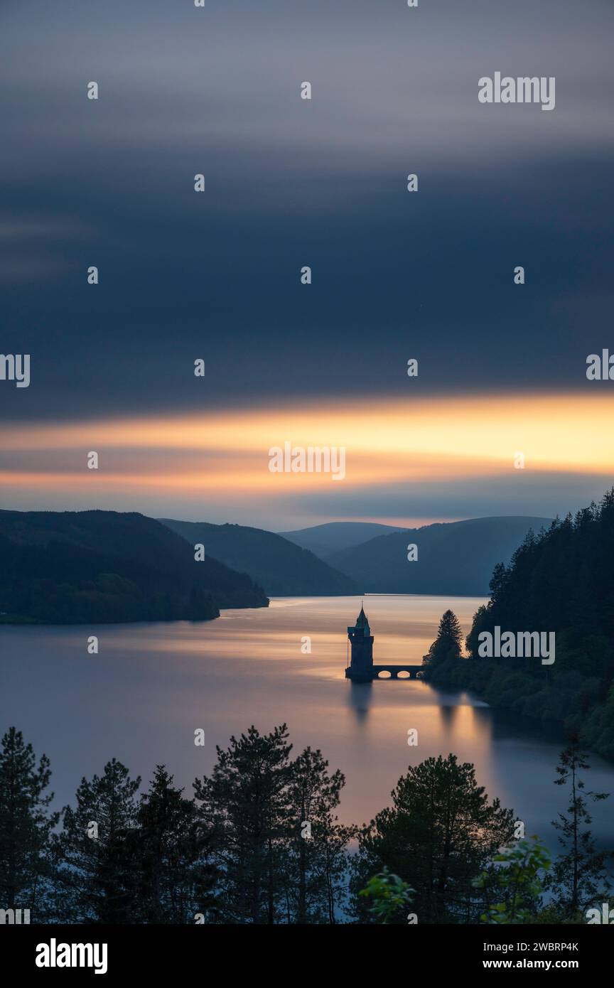 Lake Vyrnwy, in der Mitte von Wales, einer Gegend von außergewöhnlicher natürlicher Schönheit, bei Sonnenuntergang. Der orange Himmel spiegelt sich im ruhigen Wasser des Sees Stockfoto