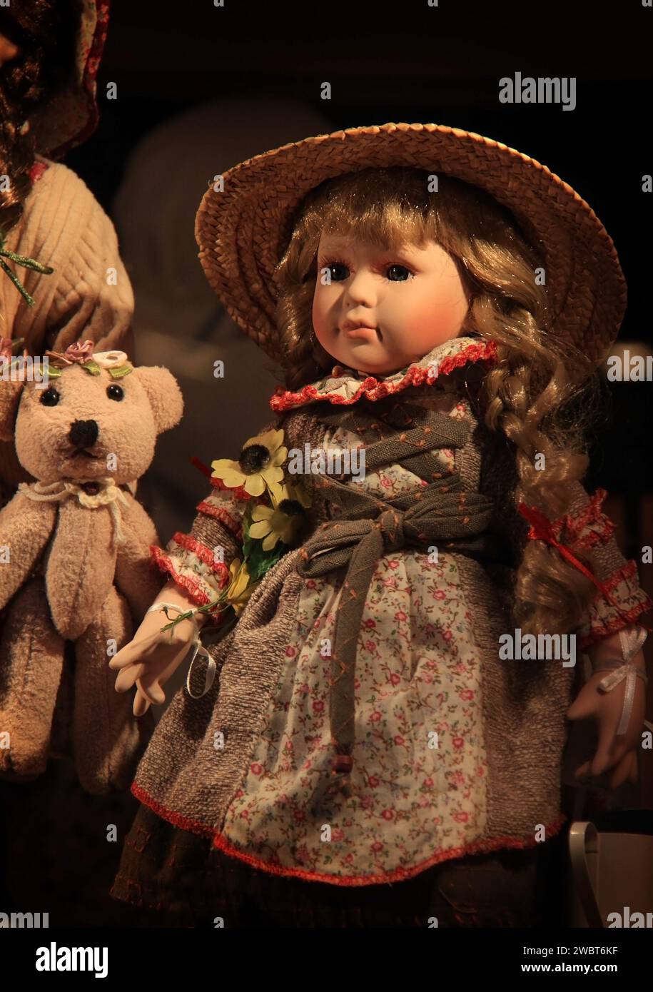 Eine hübsche Puppe mit einem hübschen Kleid und Strohhut. Stockfoto