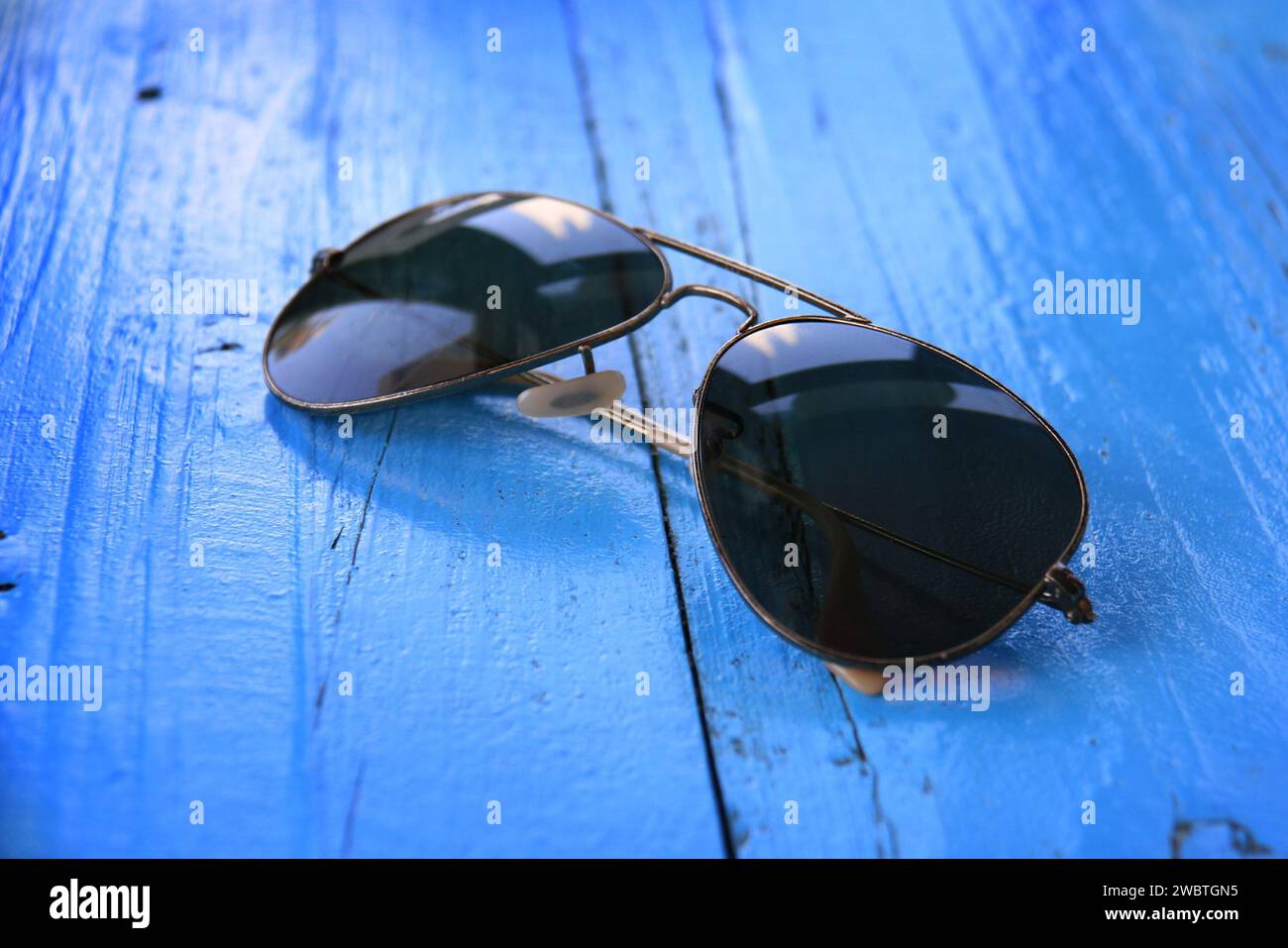 Eine Sonnenbrille auf einem blauen Holztisch. Stockfoto