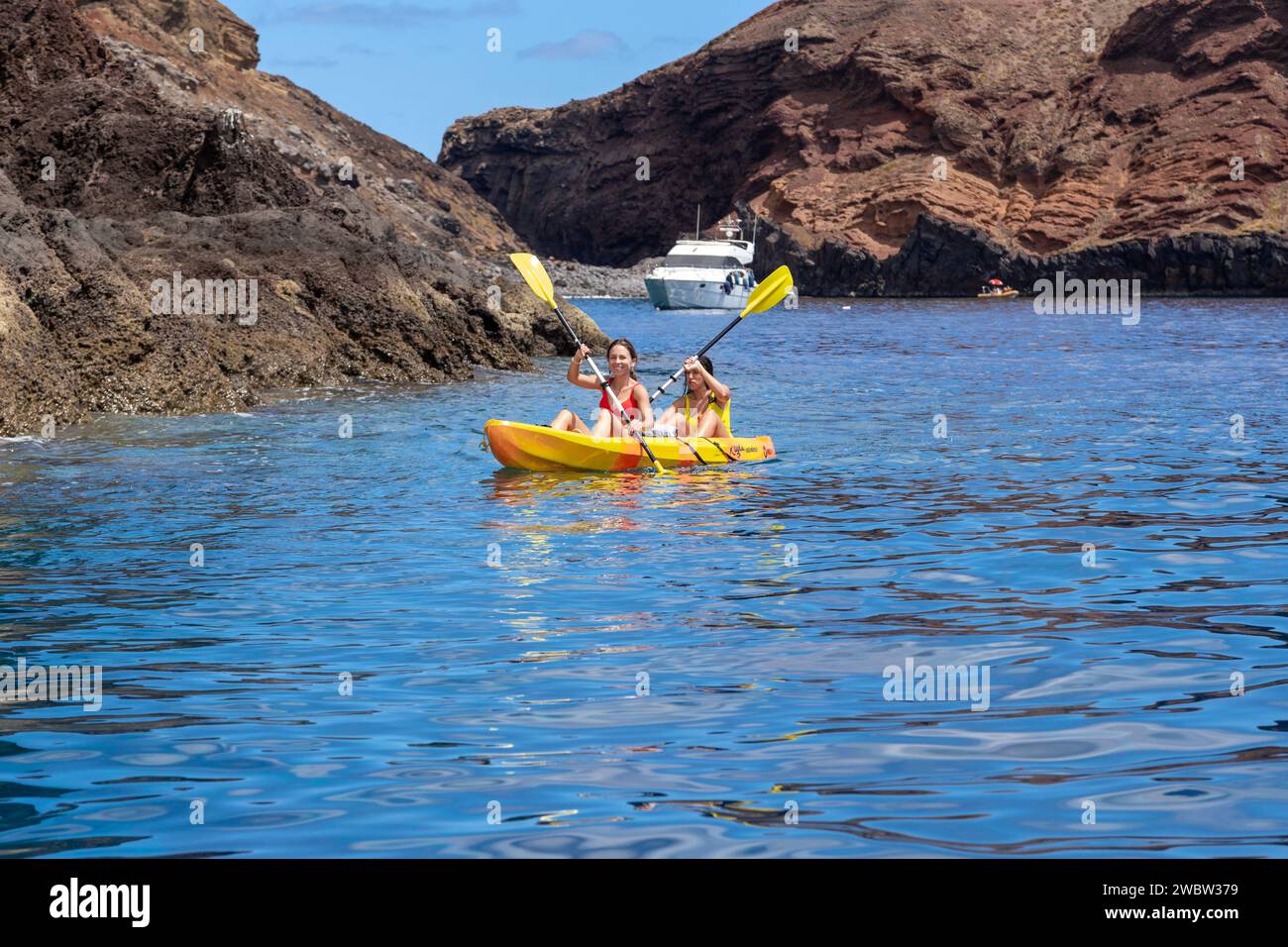 MADEIRA, PORTUGAL - 28. AUGUST 2021: Nicht identifizierte junge Frauen fahren vor den felsigen Küsten der Insel mit dem Kajak. Stockfoto MADEIRA, PORTUGAL - 28. AUGUST 2021: Nicht identifizierte junge Frauen fahren vor den felsigen Küsten der Insel mit dem Kajak. Stockfoto