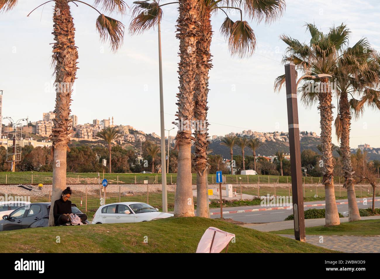 Haifa, Israel - 11. Januar 2024, spazieren Sie am Meer entlang der Promenade. Die Leute sitzen auf dem Damm, schauen auf das Meer, plaudern mit Freunden Stockfoto