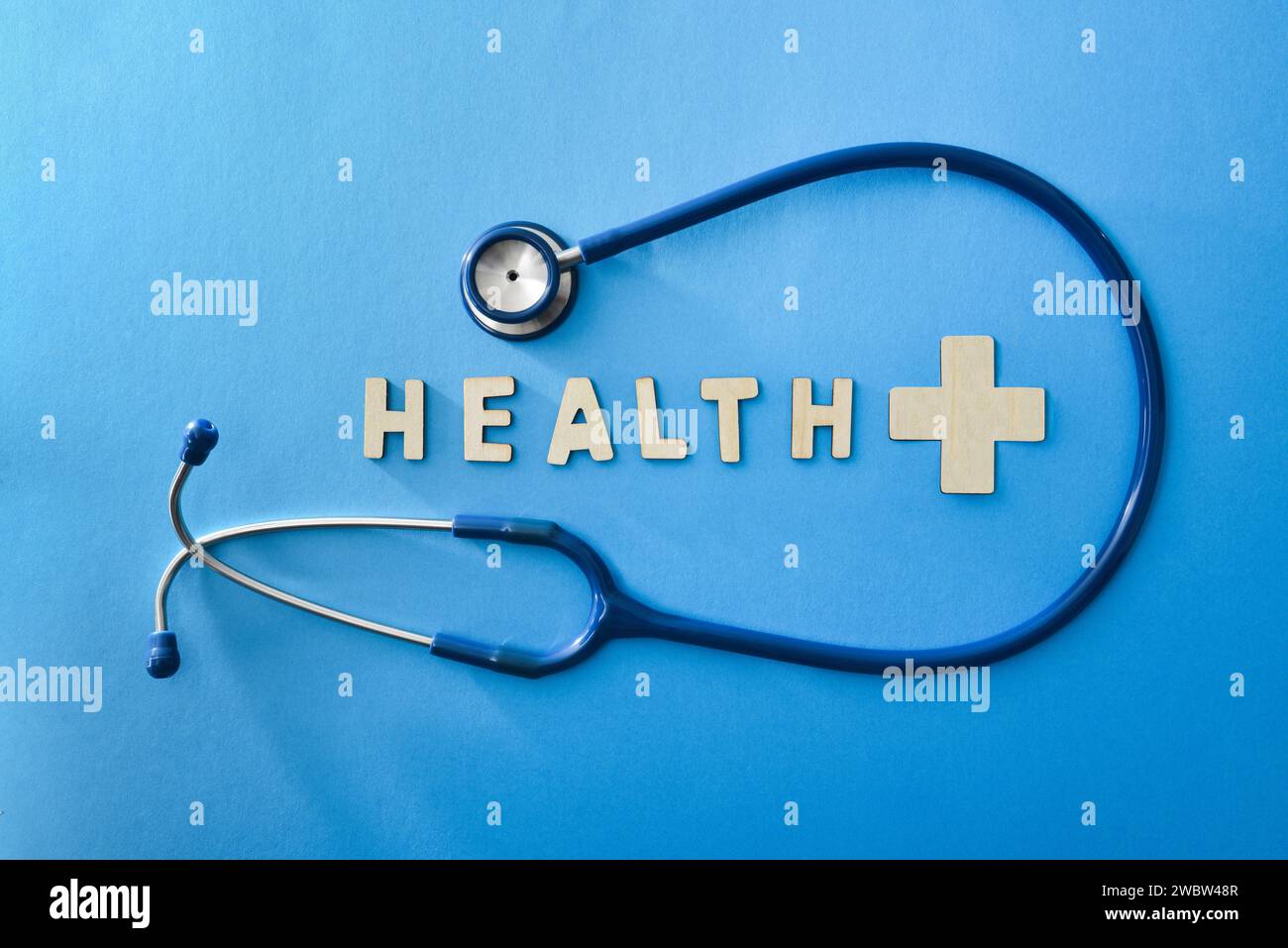 Gesundheitshintergrund mit Stethoskop und Gesundheitsbotschaft mit Holzbuchstaben auf blauem Hintergrund. Draufsicht Stockfoto