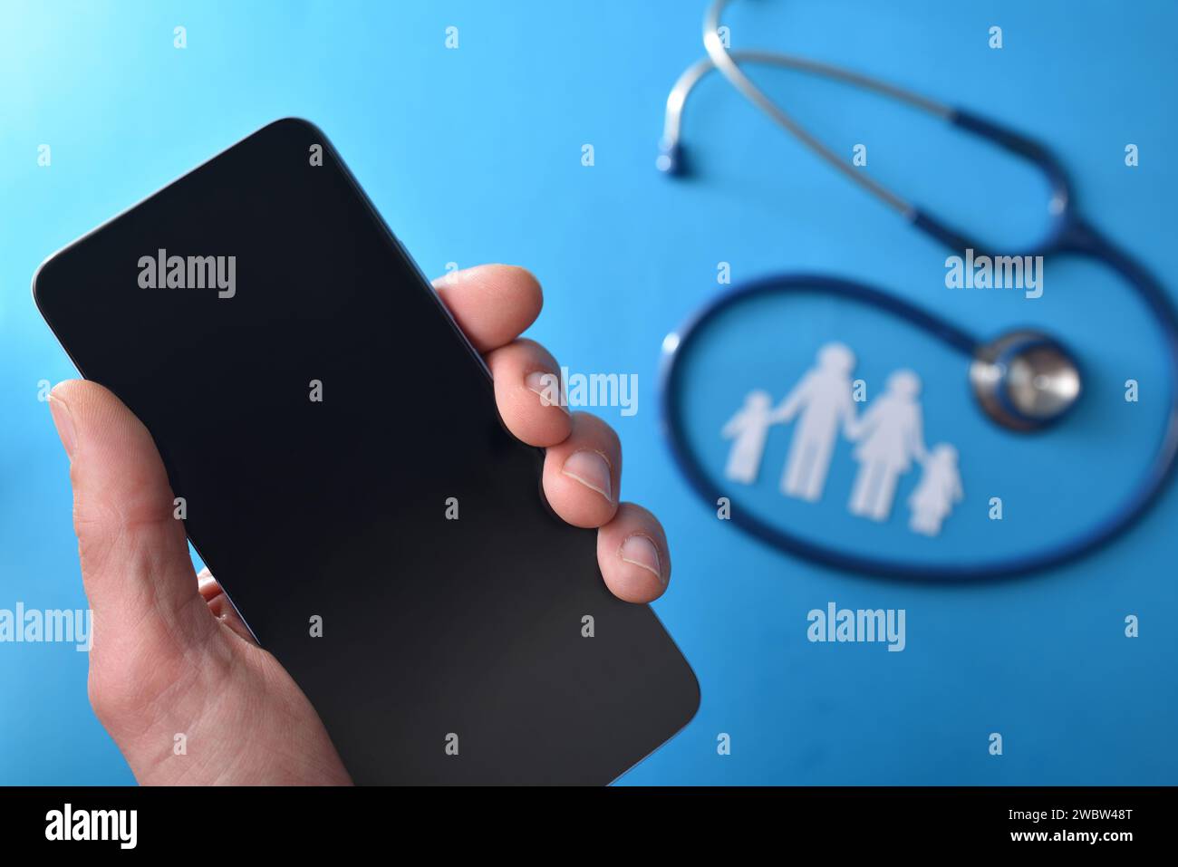 Familie Gesundheitswesen Telefon Pflege Konzept mit Hand halten ein Smartphone und Stethoskop und Ausschnitt der Familie im Hintergrund auf blauem Hintergrund. Top-Film Stockfoto