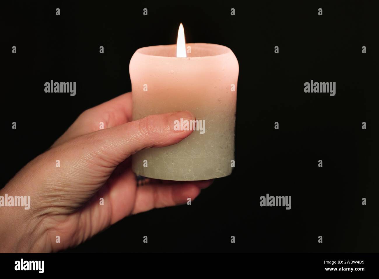 Eine Hand hält eine Kerze im Dunkeln Stockfoto