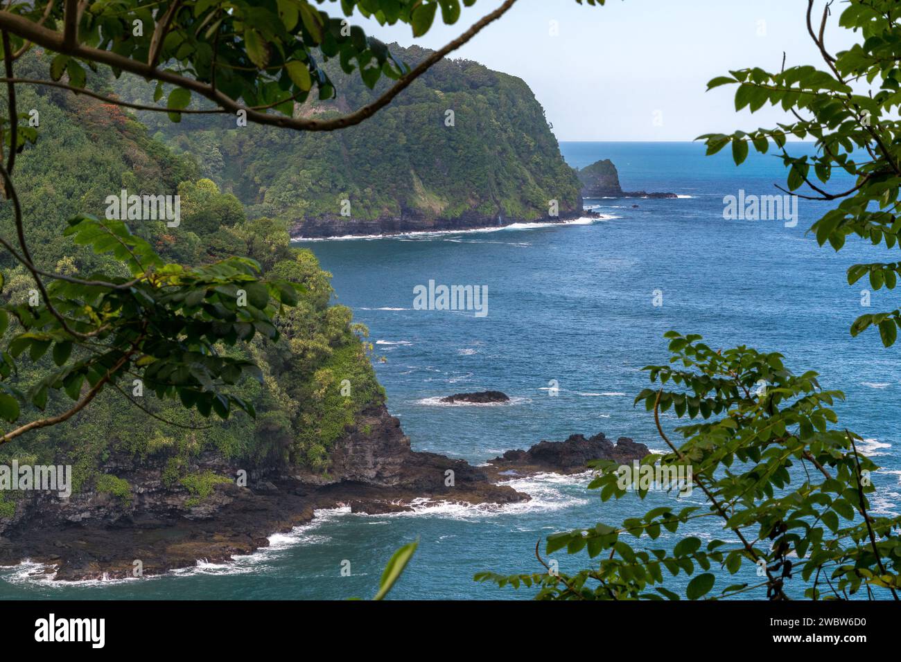 Faszinierende Küstenklippen säumen die Route nach Hana, Maui, mit atemberaubendem Blick auf den Pazifik inmitten lebendiger tropischer Vegetation. Stockfoto