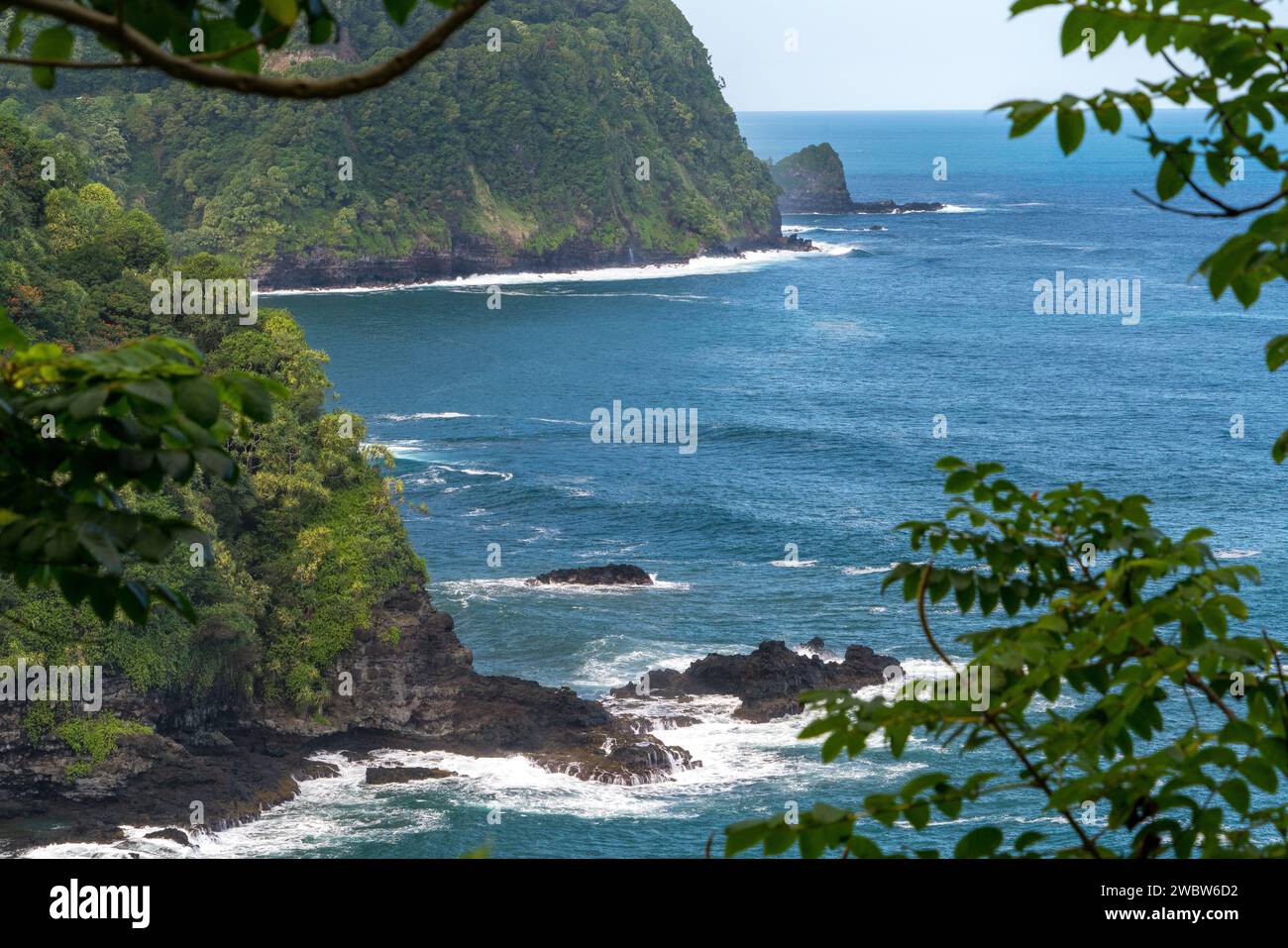 Faszinierende Küstenklippen säumen die Route nach Hana, Maui, mit atemberaubendem Blick auf den Pazifik inmitten lebendiger tropischer Vegetation. Stockfoto