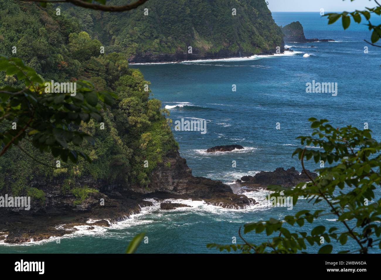 Faszinierende Küstenklippen säumen die Route nach Hana, Maui, mit atemberaubendem Blick auf den Pazifik inmitten lebendiger tropischer Vegetation. Stockfoto