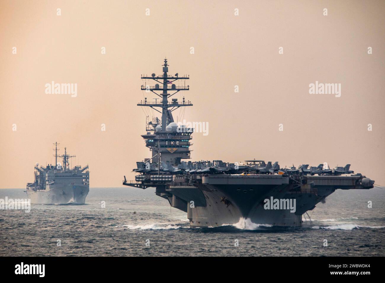 Strait of Hormuz, USA. Dezember 2023. Der US Navy-Flugzeugträger USS Dwight D. Eisenhower führt das schnelle Kampfflugschiff USNS Supply während der Operation Prosperity Guardian am 14. Dezember 2023 im Persischen Golf durch die Straße von Hormuz. Die OPG ist eine multinationale Koalition zur Unterstützung der Sicherheit im Seeverkehr und zur Bekämpfung von Angriffen auf die Handelsschifffahrt in der Region. Kredit: MC2 Keith Nowak/USA Navy Photo/Alamy Live News Stockfoto