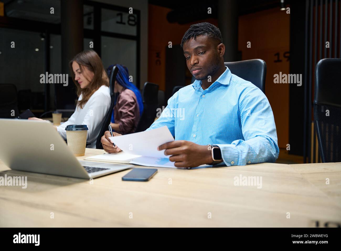 Afroamerikaner mit Kollegen, die im Büro an Laptops arbeiten Stockfoto