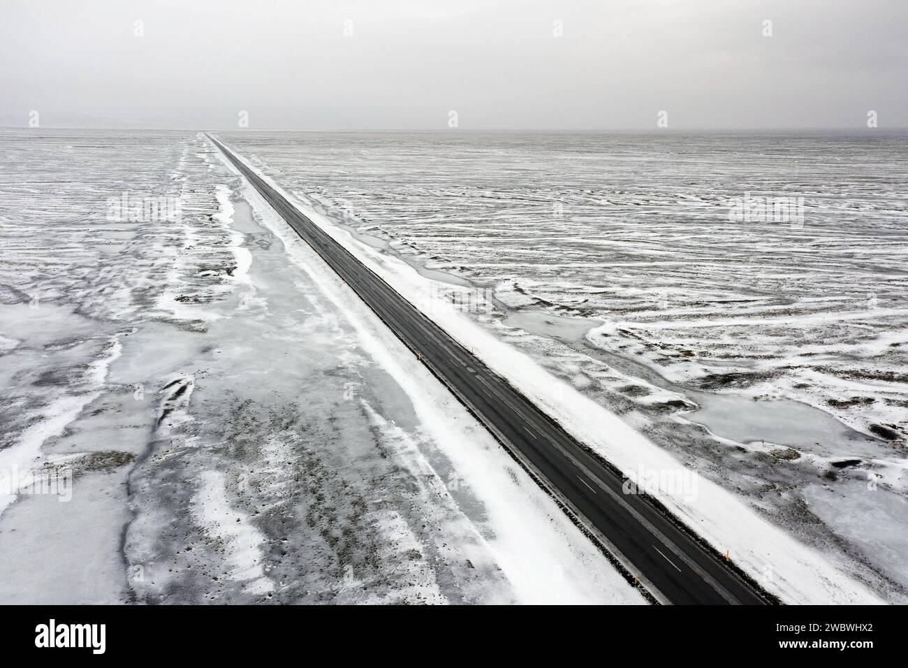 Aus der Vogelperspektive über die leere Route 1 / Ring Road, zweispurige Nationalstraße in einer verschneiten Winterlandschaft, Suðurland / Südregion, Island Stockfoto