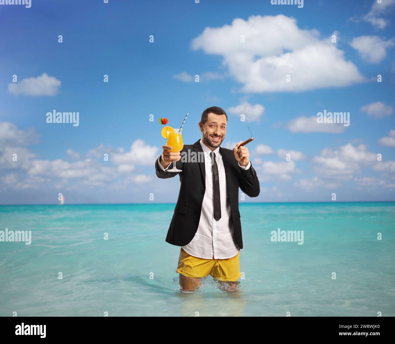 Geschäftsmann in Badeshorts mit Cocktail und Zigarre im Karibischen Meer Stockfoto