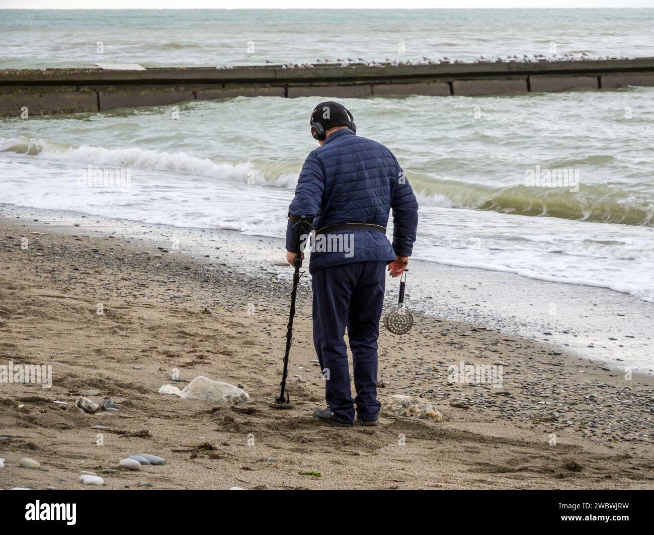 Sotschi, Russland - 2023. Februar: Suche nach Gegenständen mit einem Metalldetektor am Strand nach einem Sturm. Sotschi Stockfoto