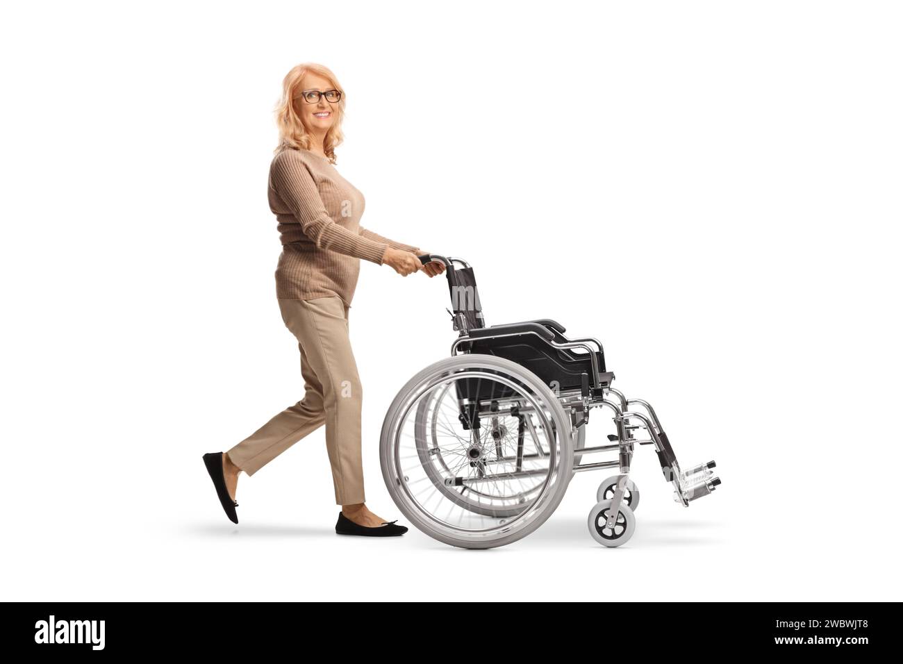 Frau mittleren Alters schiebt einen leeren Rollstuhl isoliert auf weißem Hintergrund Stockfoto