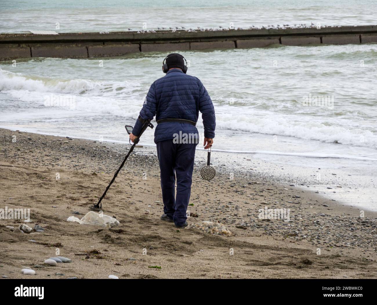 Sotschi, Russland - 2023. Februar: Ein Mann mit einem Metalldetektor am Strand nach einem Sturm. Sotschi Stockfoto
