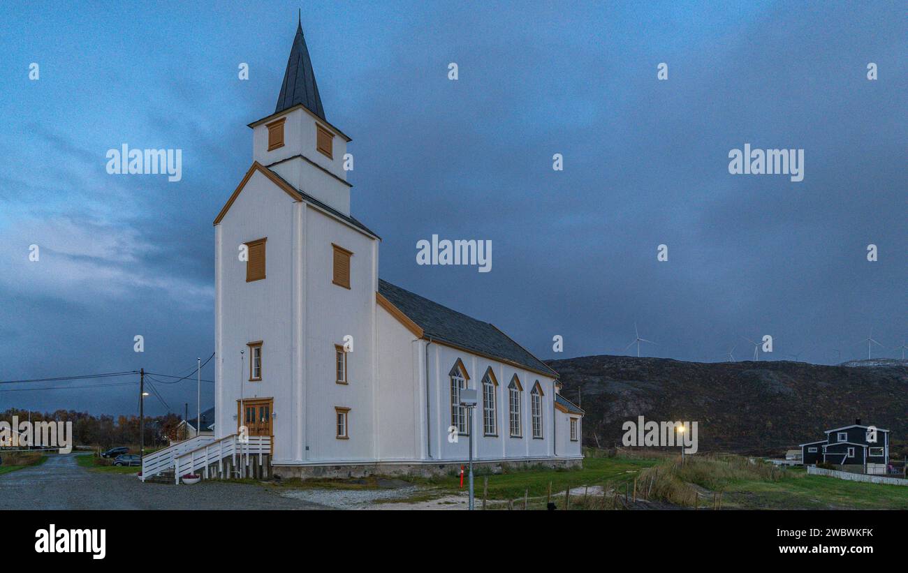 nordische weiße Kirche im Zentrum des Dorfes, mit einer großen Wiese um den Ort. Wunderschöne Kapelle in Brensholmen, Troms, Norwegen Stockfoto
