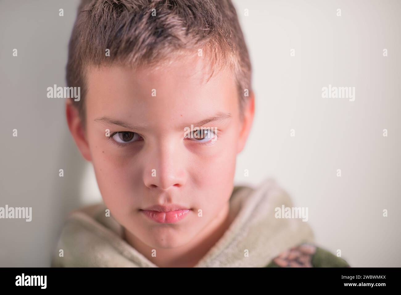 Ein Porträt eines 9-jährigen Jungen, der an der Wand steht Stockfoto