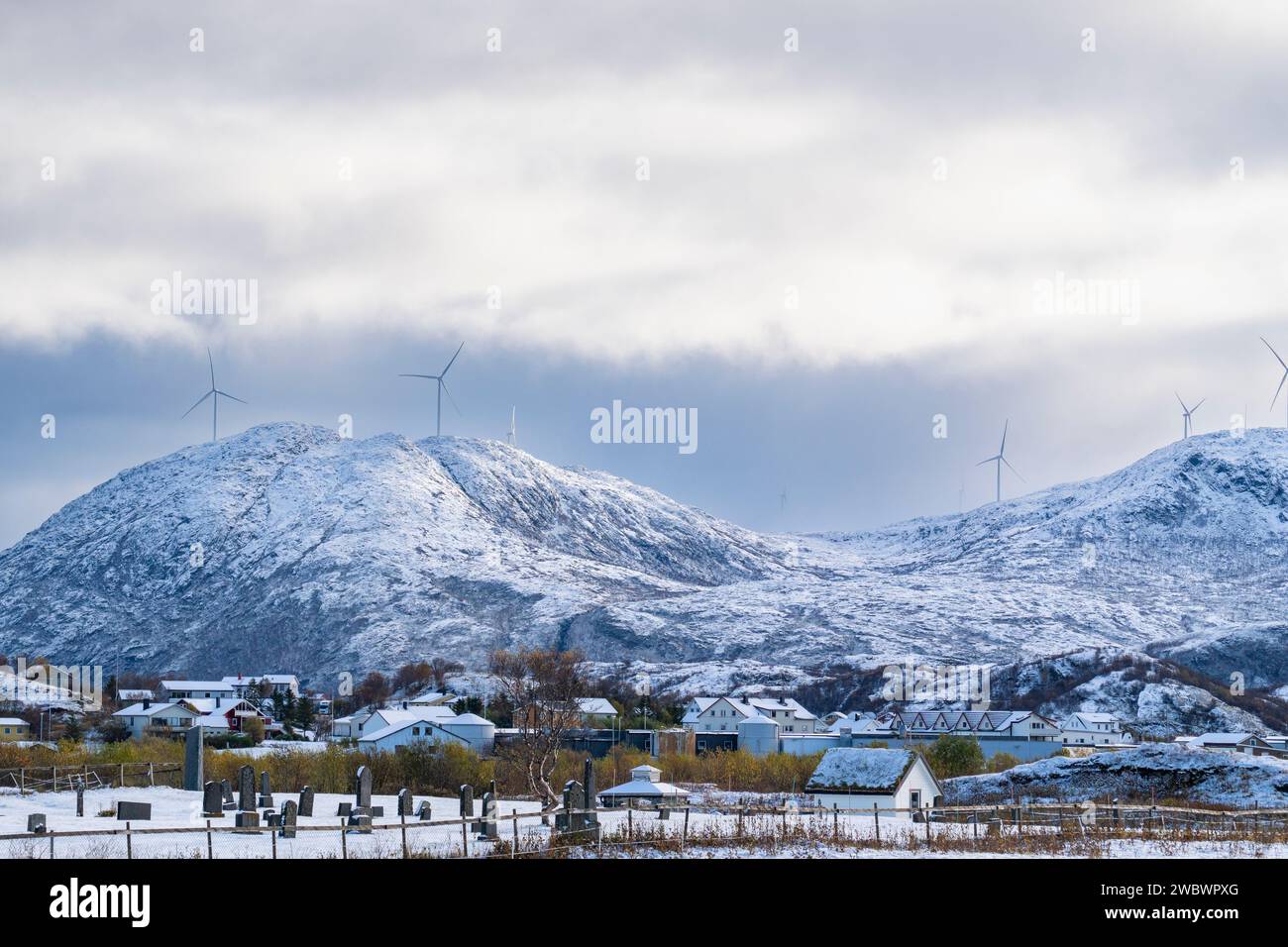 Windmühlen an der Atlantikküste bei jedem Wetter. Blick auf die frisch verschneiten Berge von der Insel Kvaløya, Norwegen, mit vielen Windturbinen Stockfoto