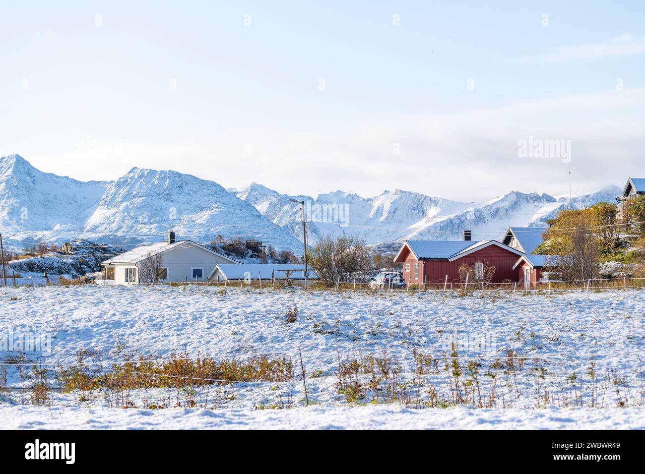 Intelligente Häuser auf der Insel Hillesøya, Norwegen, mit schneebedeckten Bergen im Hintergrund! Ferienhaus, Hütte, Hütte im Winter an einem sonnigen Tag mit Wolken Stockfoto