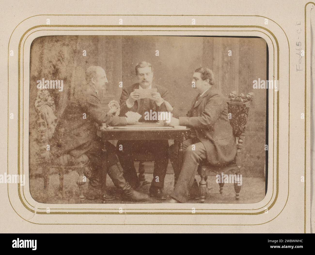 Gruppenporträt von drei Männern Kartenspiel und Lesen, Carel Eduard Westerborg, 1861 - 1890 Foto. Cabinet Foto dieses Foto ist Teil eines Albums. Arnheim-Karton. Fotografische Trägeralbumen drucken anonyme historische Personen, die in einer Gruppe dargestellt werden, in einem Gruppenporträt. Spielkarten Stockfoto