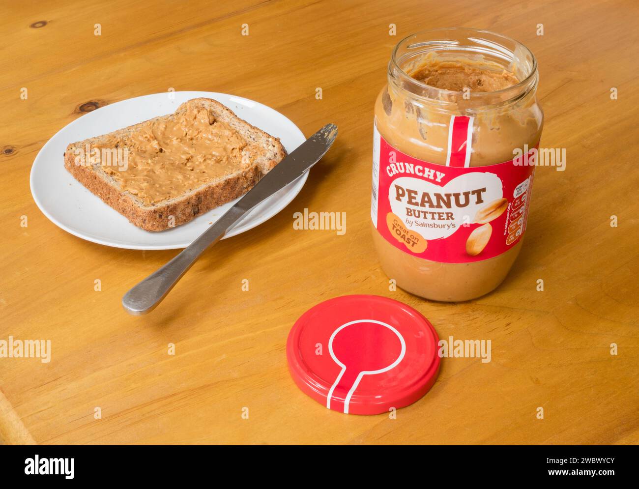 Ein Glas mit Sainsbury's knuspriger Erdnussbutter und eine Scheibe Toast mit Erdnussbutter, England, Großbritannien Stockfoto