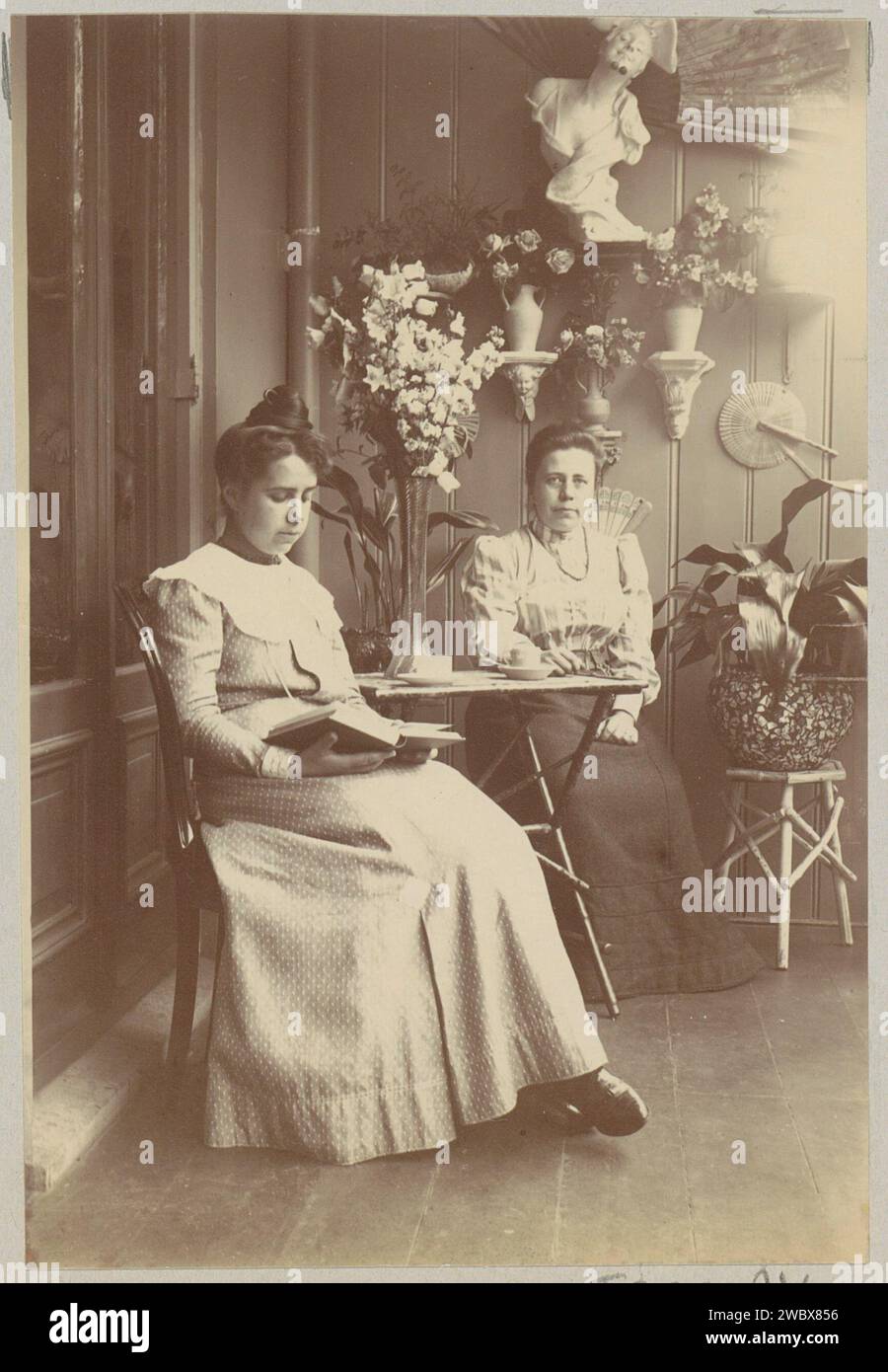 Zwei Frauen, sitzen in einem Konservatorium, eine Lesung, anonym, ca. 1900 - ca. 1910 Foto Teil des Familienalbums mit Fotos von Wijnhandel Kraaij & Co. Bordeaux-Amsterdam. Fotografische Unterstützung beim Lesen Stockfoto