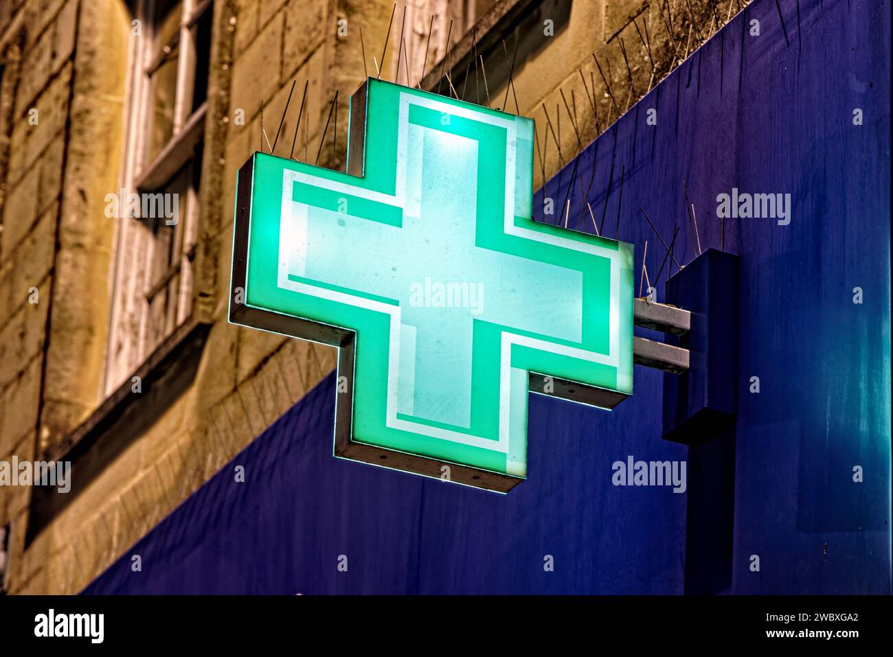 Warminster, Wiltshire, Vereinigtes Königreich - 29. Dezember 2022: Ein beleuchtetes grünes erste-Hilfe-Kreuz an der Fassade von Boots the Chemist in The Warminster, England Stockfoto
