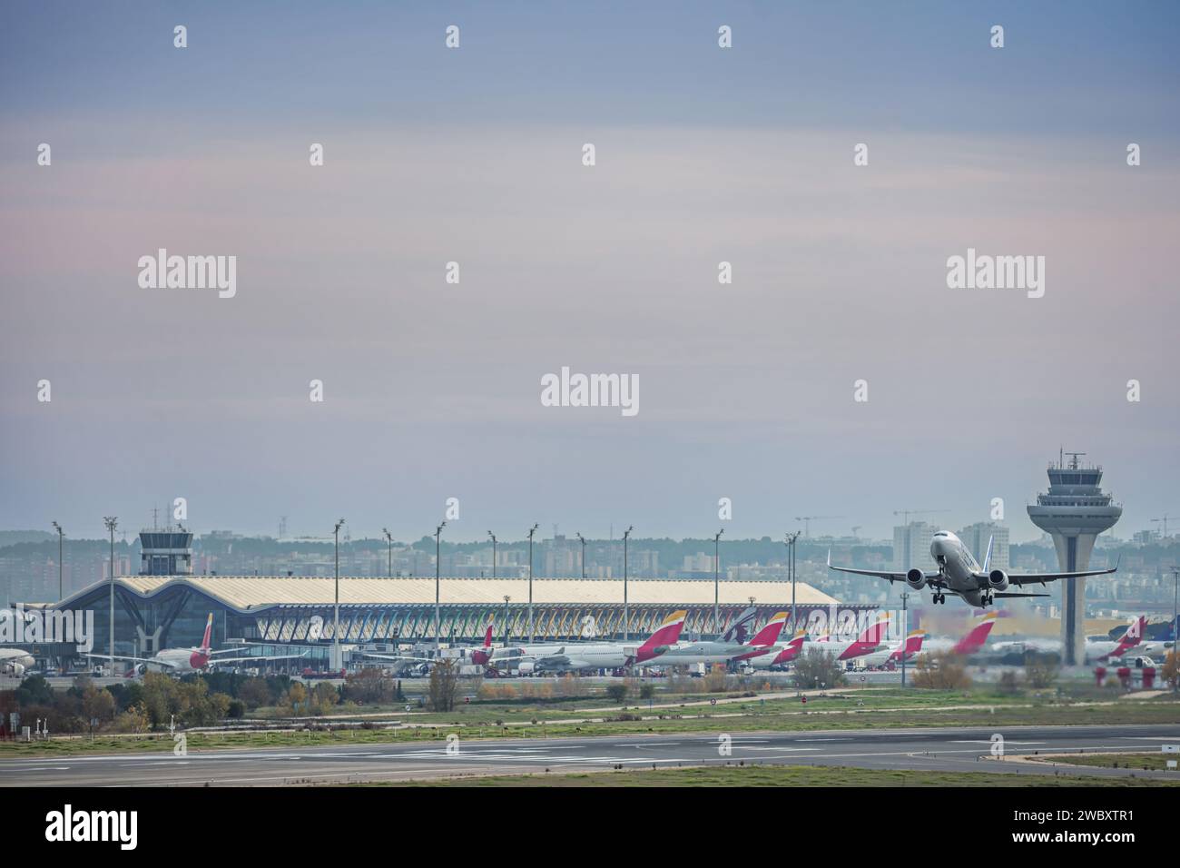 Start- und Landebahn, Terminal 4, Kontrollturm und ein Flugzeug, das mit voller Geschwindigkeit startet Stockfoto