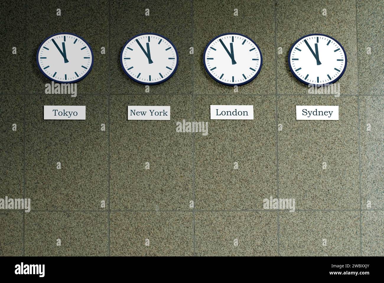Vier Uhren an einer Wand, die die Weltzeit von Tokio, London, New York und Sydney anzeigen, alle von ihnen sind fünf bis zwölf, was darauf hinweist, dass es höchste Zeit ist Stockfoto
