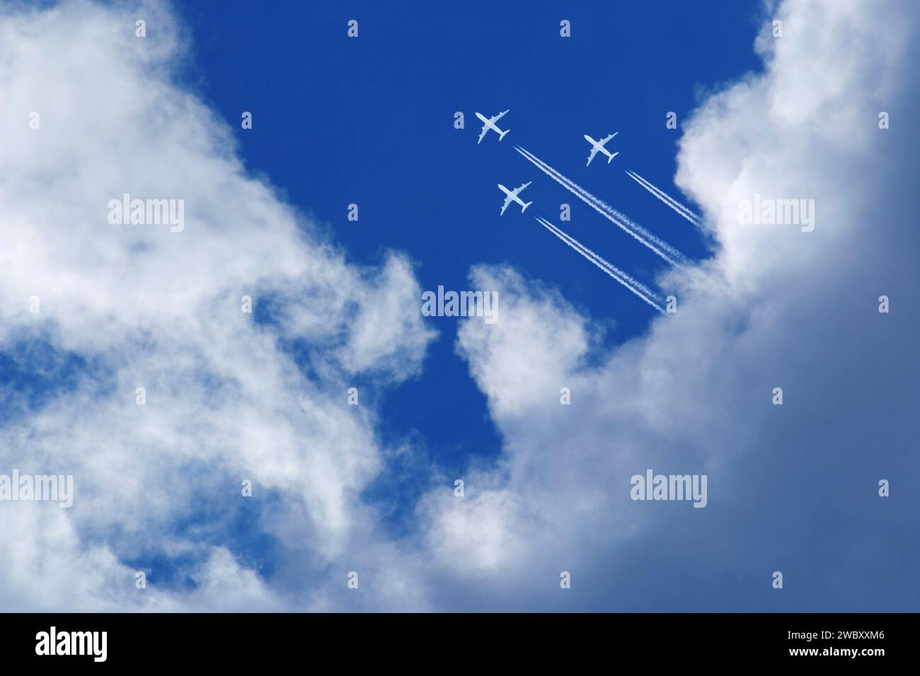 Drei Flugzeuge hoch am blauen Himmel, fliegende Formation mit Kondensstreifen zwischen weißen Wolken Stockfoto