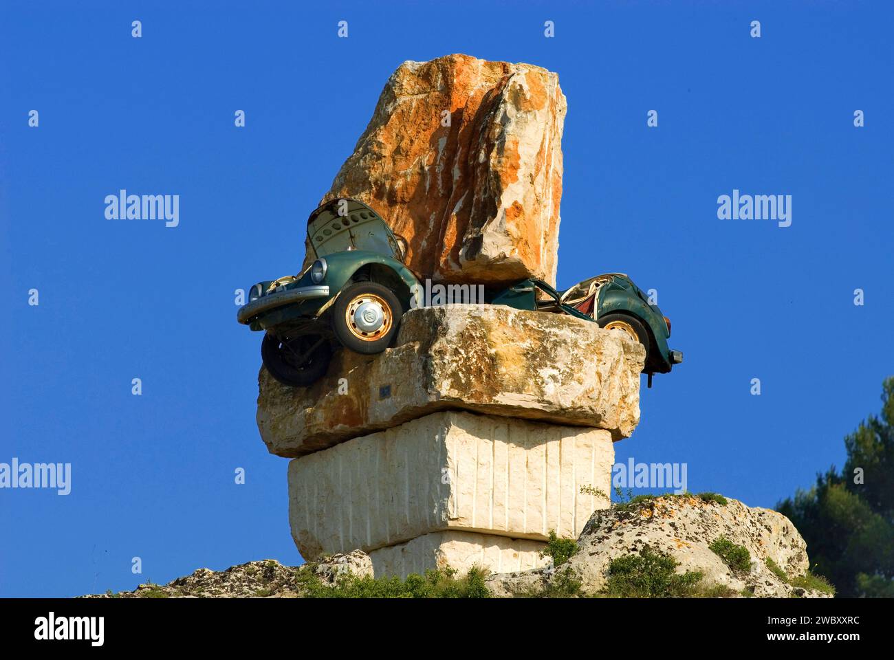 Kunst in Süditalien, ein grüner VW-Käfer, der zwischen riesigen Felsbrocken total zerquetscht wurde, Italien, Europa Stockfoto