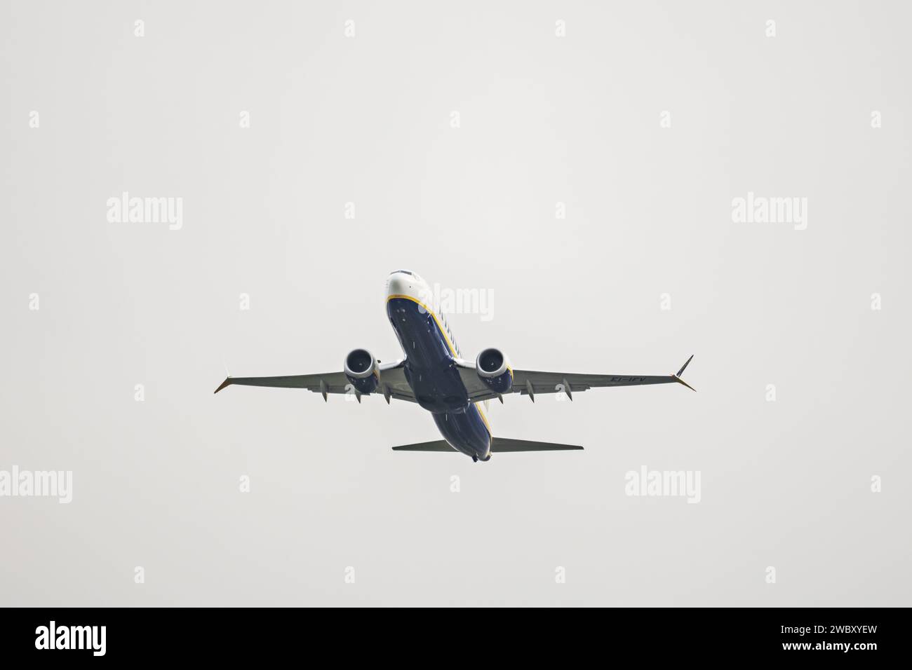 Blau lackierter Rumpf an der Unterseite eines Passagierflugzeugs einer bekannten europäischen Firma, die über einen grauen Himmel fliegt Stockfoto