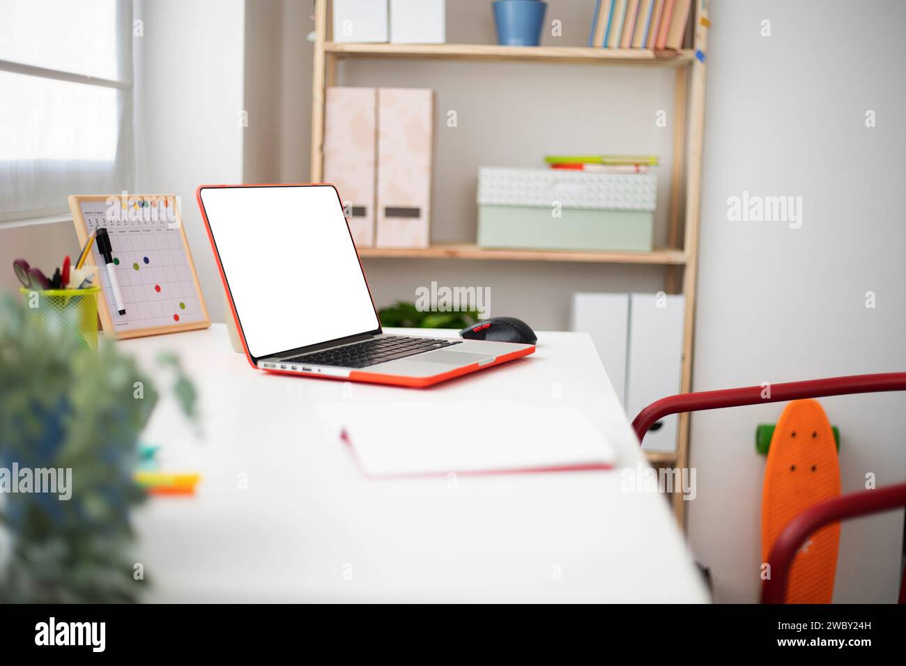 Laptop mit leerem Bildschirm auf dem Schülertisch in einem hellen Teenager-Zimmer Stockfoto