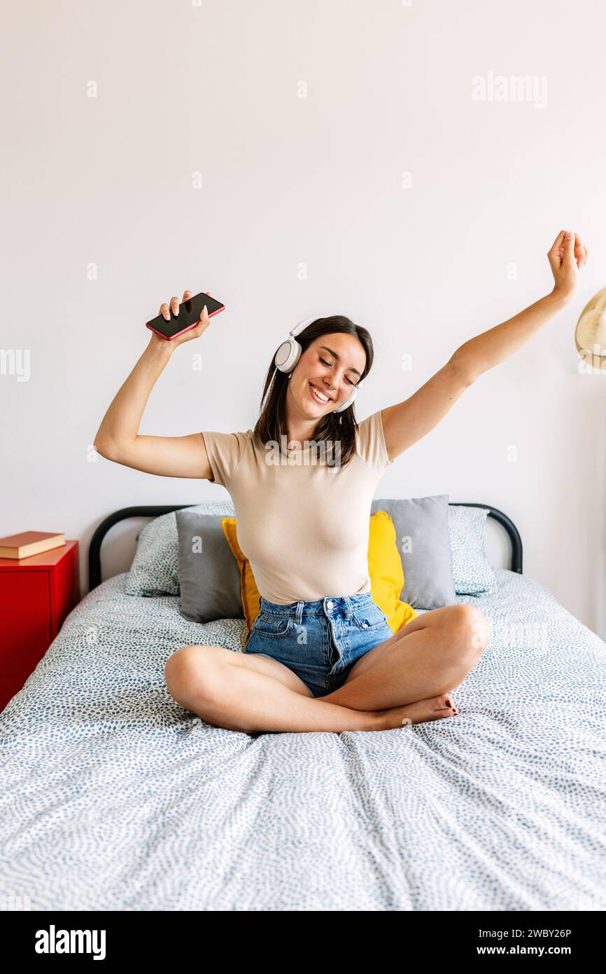 Junge glückliche Frau, die Online-Musik genießt, während sie sich zu Hause entspannt Stockfoto